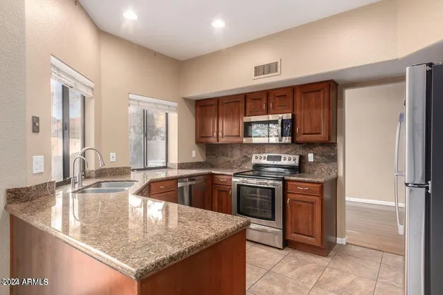 a kitchen with stainless steel appliances granite countertop a sink stove and refrigerator