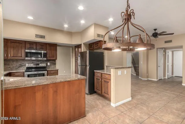 a kitchen with stainless steel appliances granite countertop a refrigerator a stove a sink and a microwave