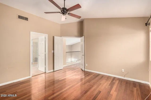 an empty room with wooden floor and ceiling fan
