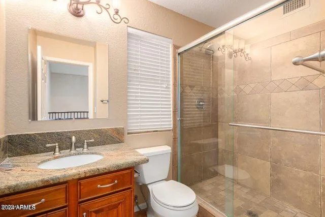 a bathroom with a granite countertop sink toilet mirror and shower