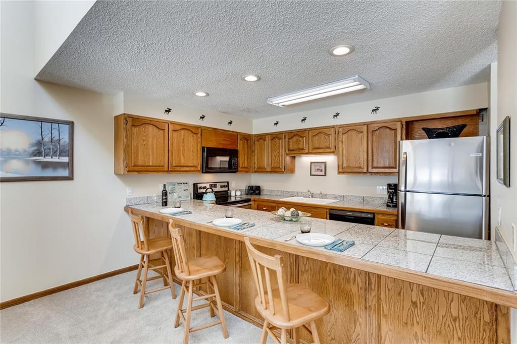 760 Copper Road, Unit 201 Copper Mountain, CO 80443 - Photo 8 of 28 a kitchen with stainless steel appliances granite countertop a refrigerator a sink a stove a dining table and chairs with wooden floor