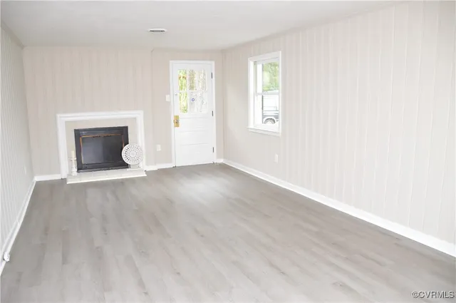 an empty room with wooden floor windows and fireplace