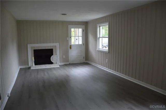an empty room with wooden floor fireplace and windows