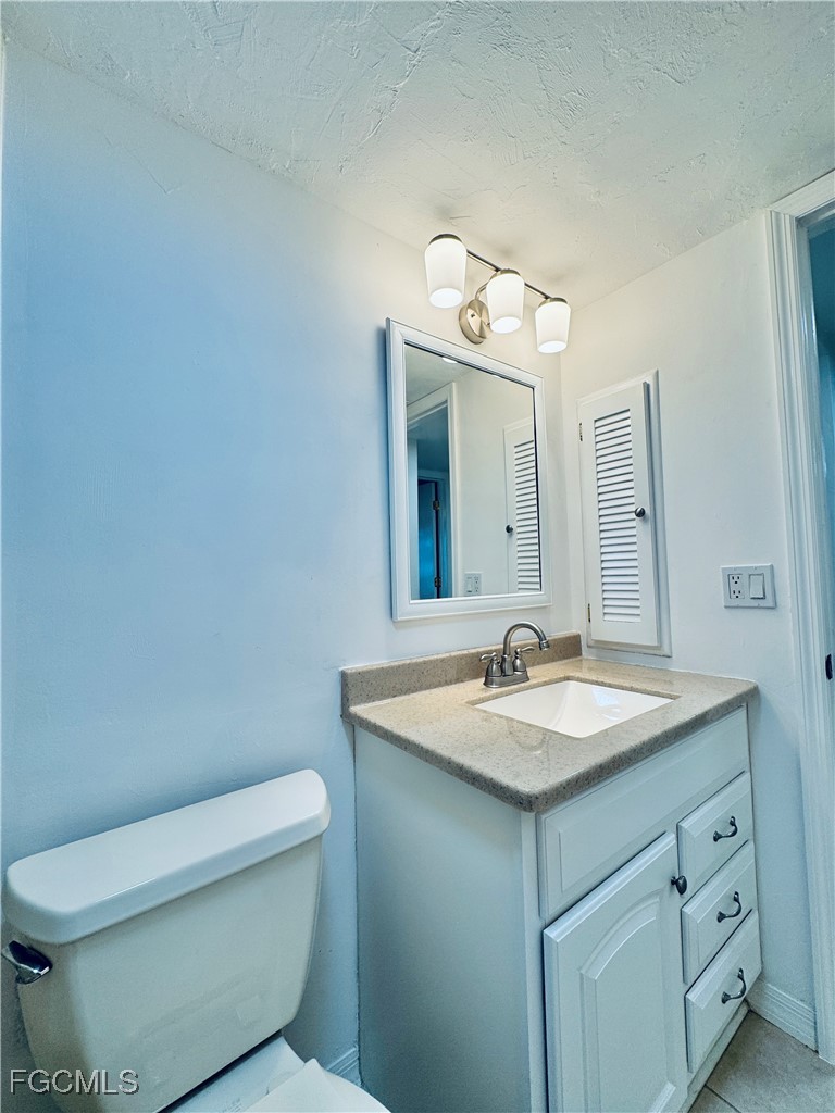 2711 First Street, Unit 102 Fort Myers, FL 33916 - Photo 21 of 36 a bathroom with a granite countertop toilet sink and mirror