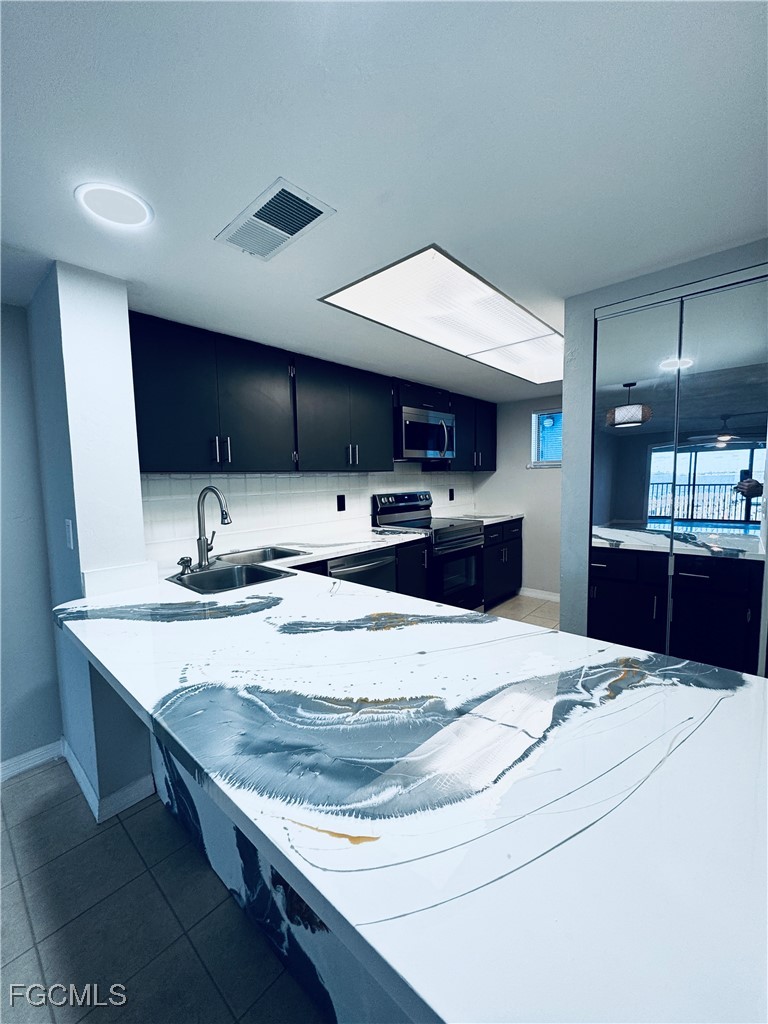 2711 First Street, Unit 102 Fort Myers, FL 33916 - Photo 6 of 36 a kitchen with stainless steel appliances kitchen island a sink and a refrigerator