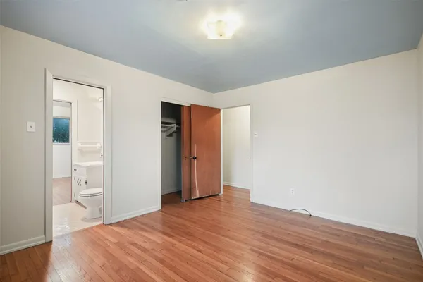 a view of an empty room with wooden floor and closet