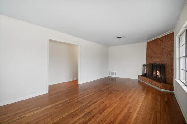a view of an empty room with wooden floor and a fireplace
