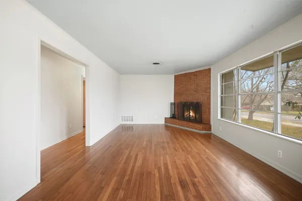 a view of empty room with wooden floor and fireplace