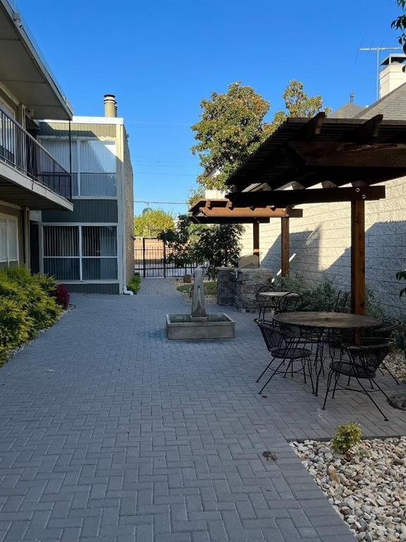 4020 Rawlins Street, Unit 102 Dallas, TX 75219 - Photo 10 of 11 a view of a patio with a table and chairs under an umbrella