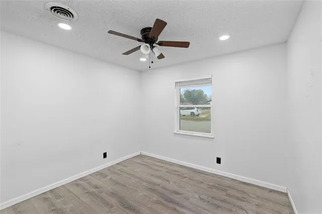 an empty room with a window and ceiling fan