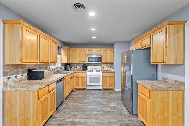 a large kitchen with stainless steel appliances granite countertop a stove a sink dishwasher and a refrigerator