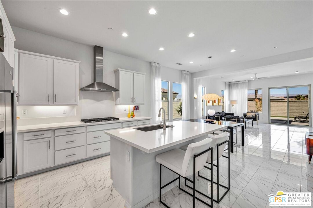 64 Claret Road Rancho Mirage, CA 92270 - Photo 3 of 30 a kitchen with stainless steel appliances kitchen island granite countertop a stove a sink a dining table and chairs with wooden floor