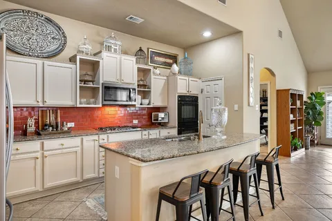 a kitchen with stainless steel appliances granite countertop a kitchen island a stove and a sink