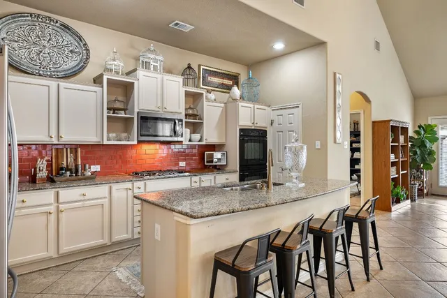 a kitchen with stainless steel appliances granite countertop a kitchen island a stove and a sink