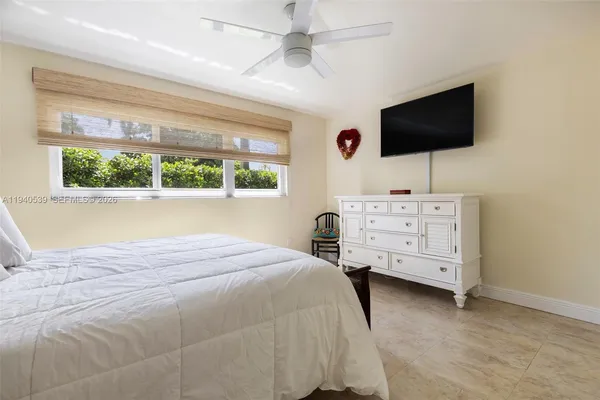 a bedroom with a bed and flat tv screen on the dresser