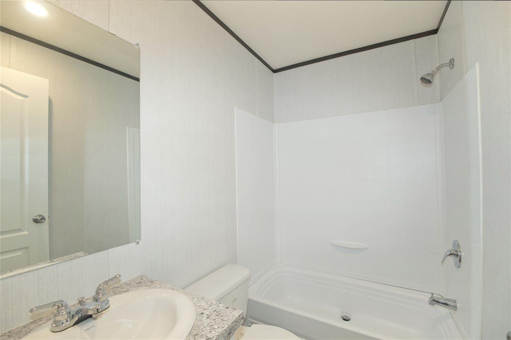 60 Tecumseh Road Valley View, TX 76272 - Photo 17 of 20 Bathroom featuring a white tub/shower combination, a vanity with a granite-look countertop, an integrated sink, and a chrome faucet