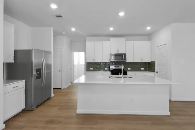 a large white kitchen with stainless steel appliances