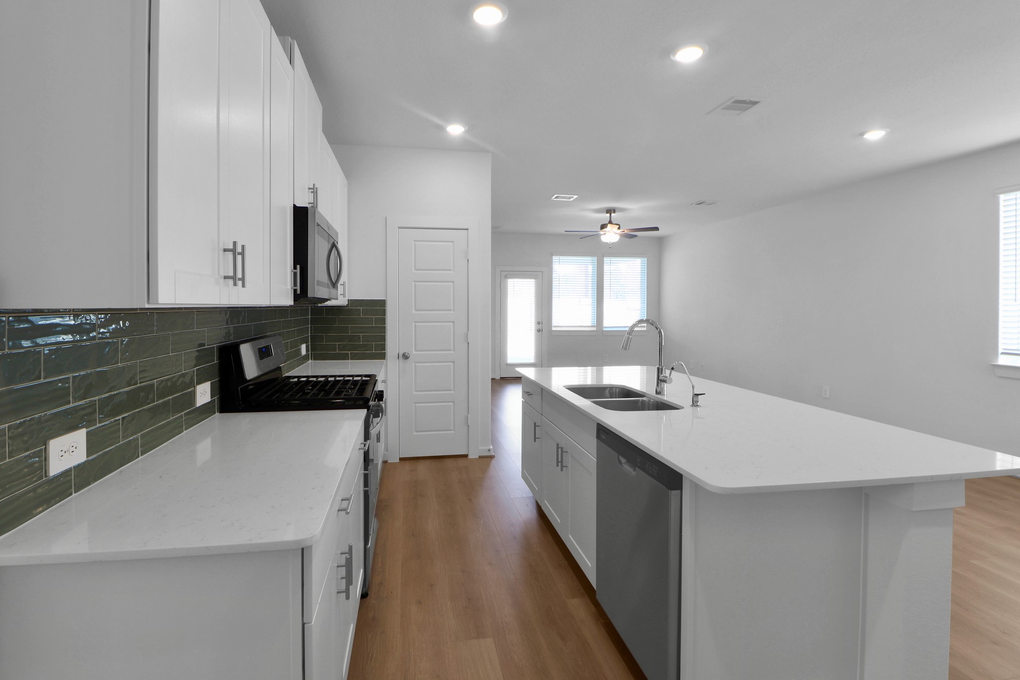 2614 Cactus Ranch Lane Crosby, TX 77532 - Photo 5 of 24 a large white kitchen with a sink and dishwasher a stove top oven with wooden floor