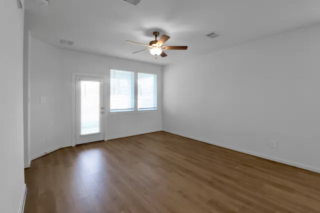 a view of an empty room with wooden floor and a window