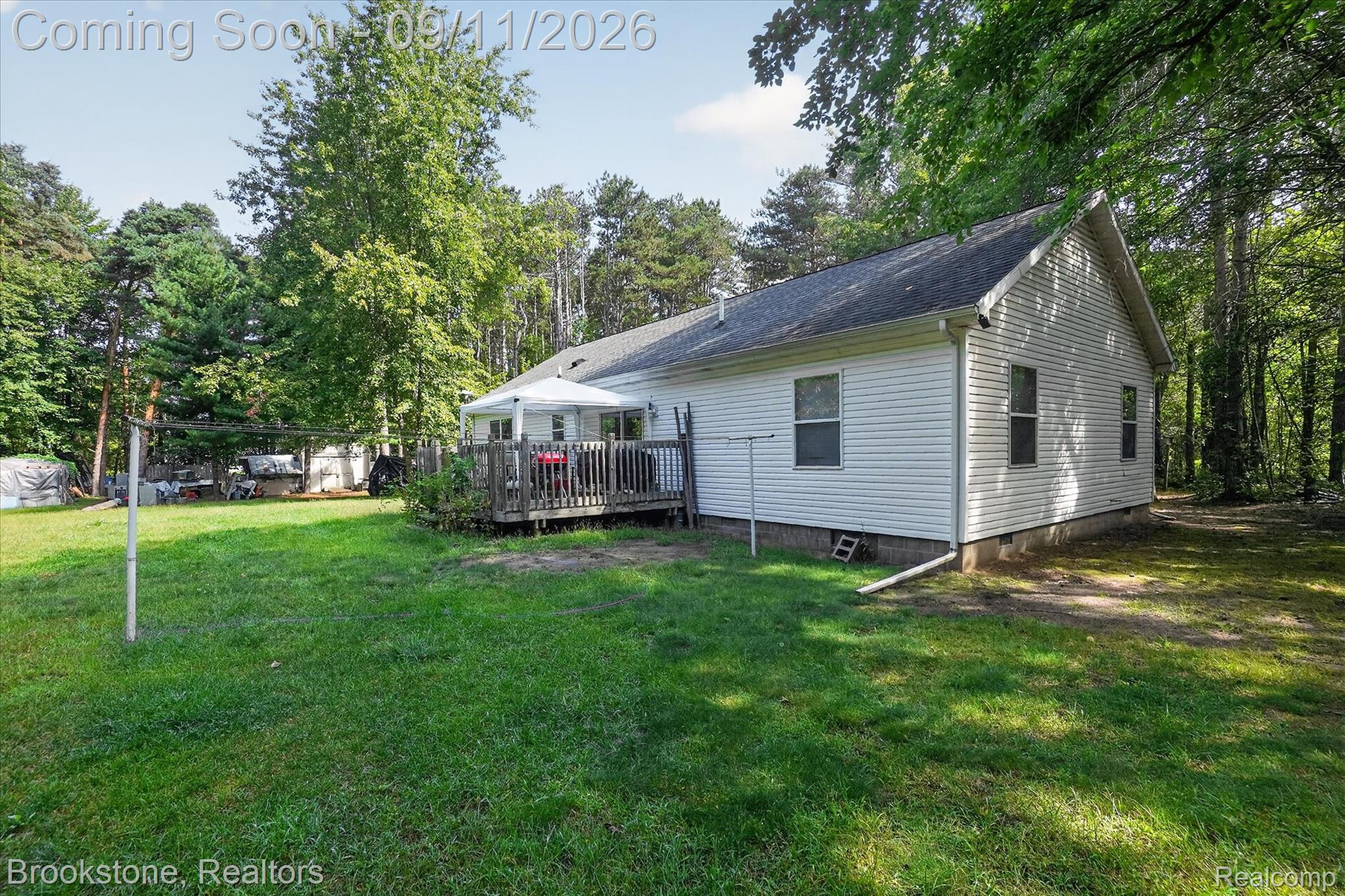 1812 South Steel Road Merrill, MI 48637 - Photo 28 of 39 White siding exterior, dark shingle roof, expansive green lawn, wood deck, surrounding mature trees