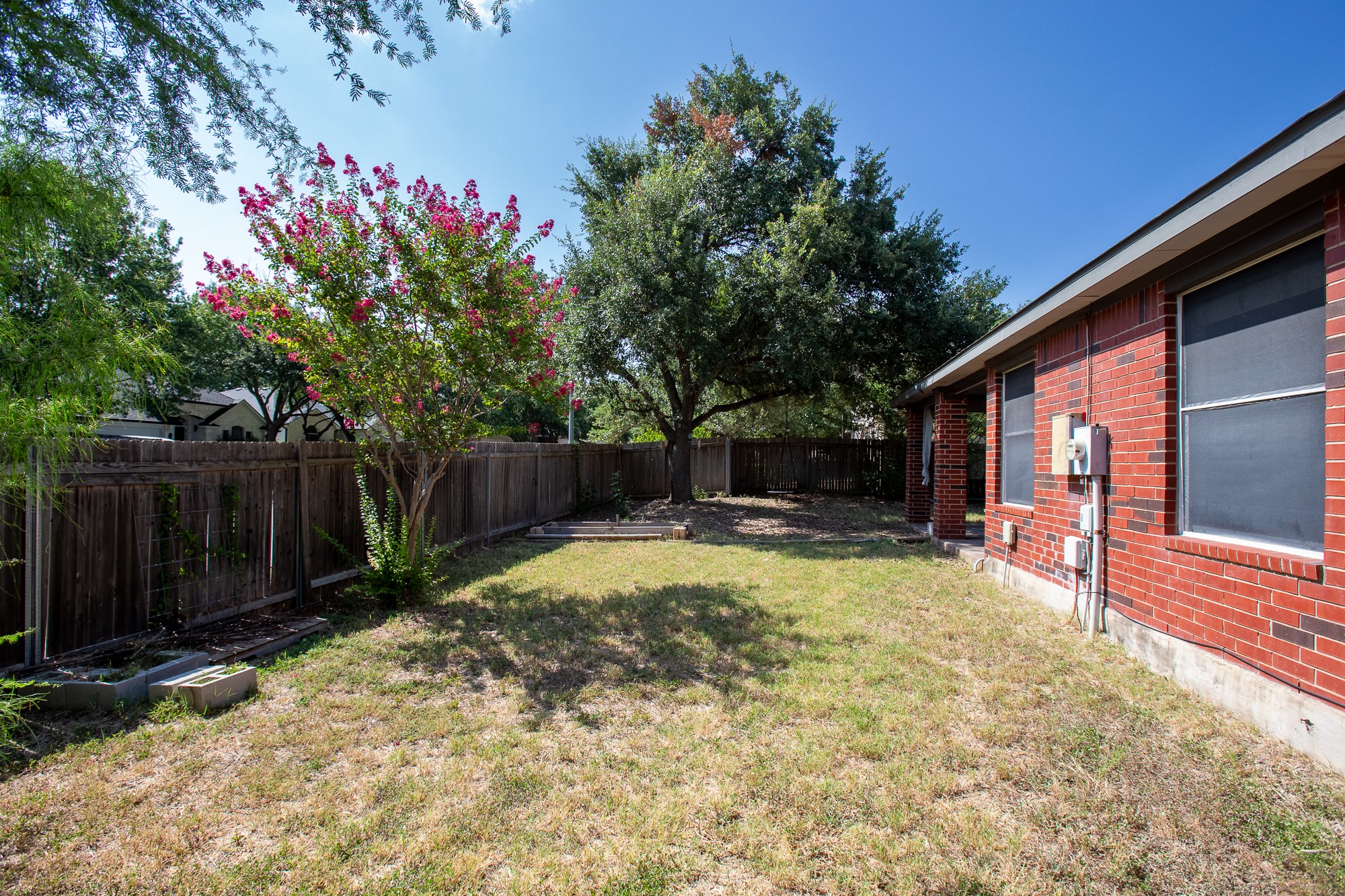 1201 Springbrook Road Pflugerville, TX 78660 - Photo 31 of 33 A well-maintained fenced yard offers a private outdoor sanctuary with mature trees and a blooming crepe myrtle.