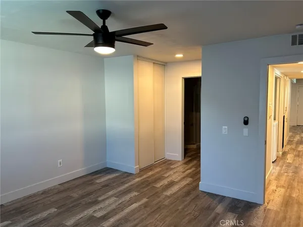 en empty room with wooden floor and a ceiling fan