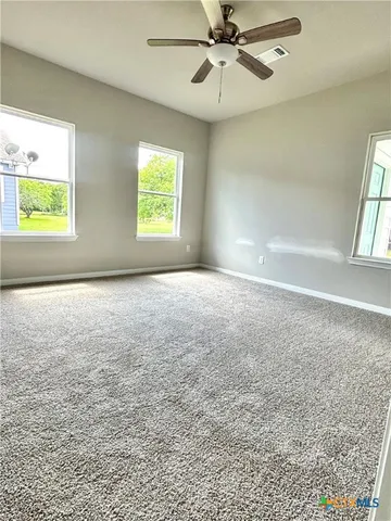 an empty room with windows and fan