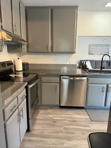 a kitchen with stainless steel appliances granite countertop a sink a stove and a wooden floors