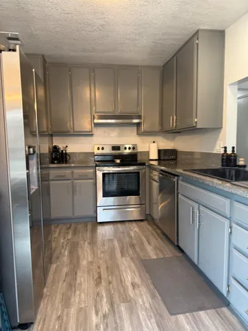 a kitchen with granite countertop a sink stainless steel appliances and cabinets