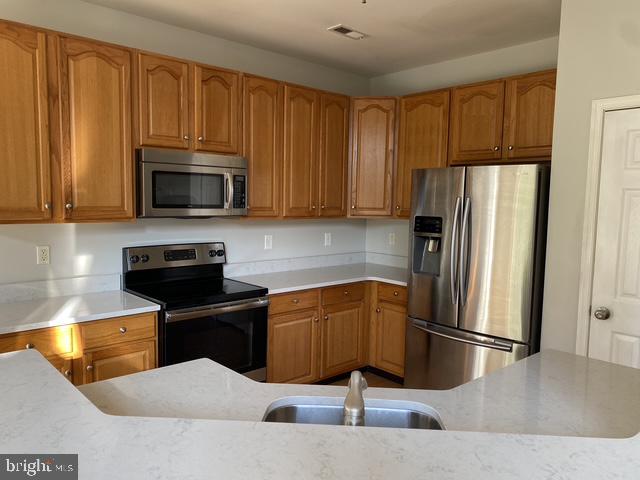 5128 Barness Court Doylestown, PA 18902 - Photo 10 of 27 a kitchen with stainless steel appliances wooden cabinets a stove a microwave and a window