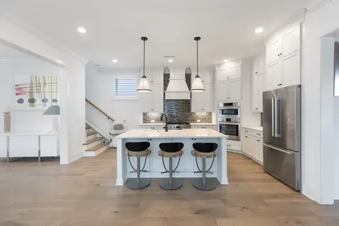 a kitchen with stainless steel appliances granite countertop a sink a stove a refrigerator and island with wooden floor