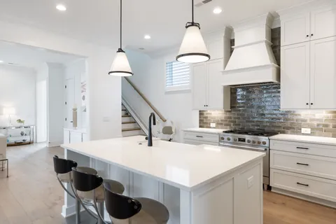 a kitchen with stainless steel appliances kitchen island a table chairs in it and white cabinets