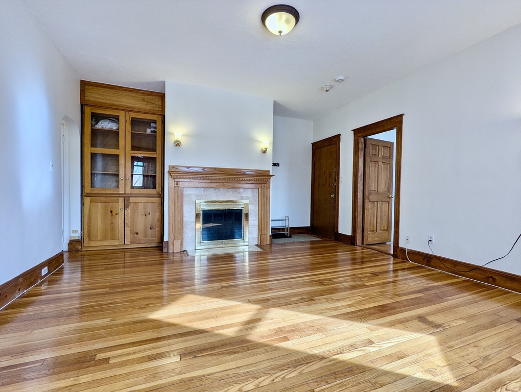 a view of empty room with wooden floor and fireplace