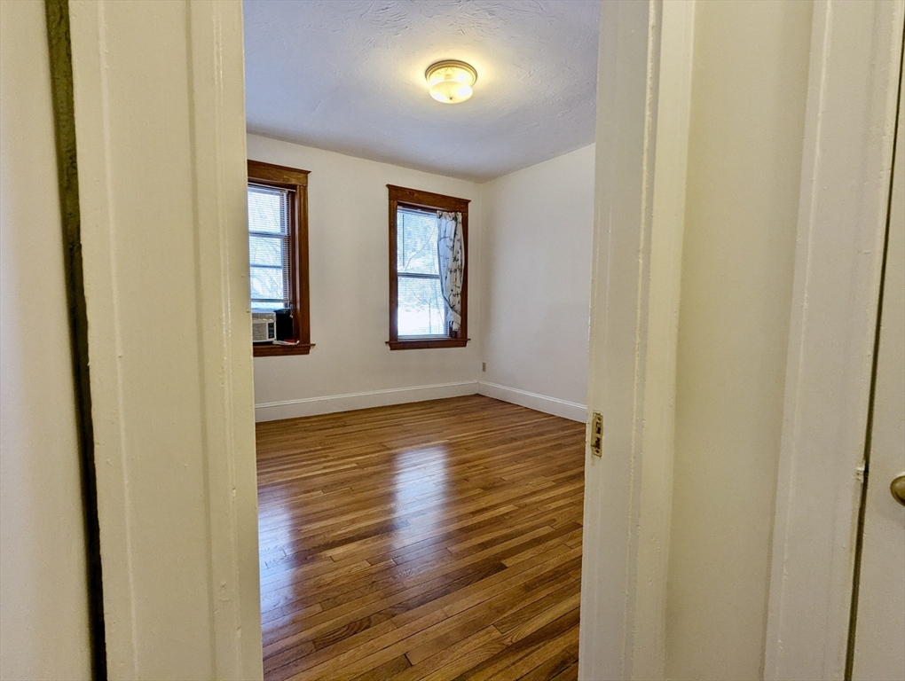 21 Westbourne Terrace, Unit 3 Brookline, MA 02446 - Photo 18 of 23 a view of an empty room with wooden floor and a window
