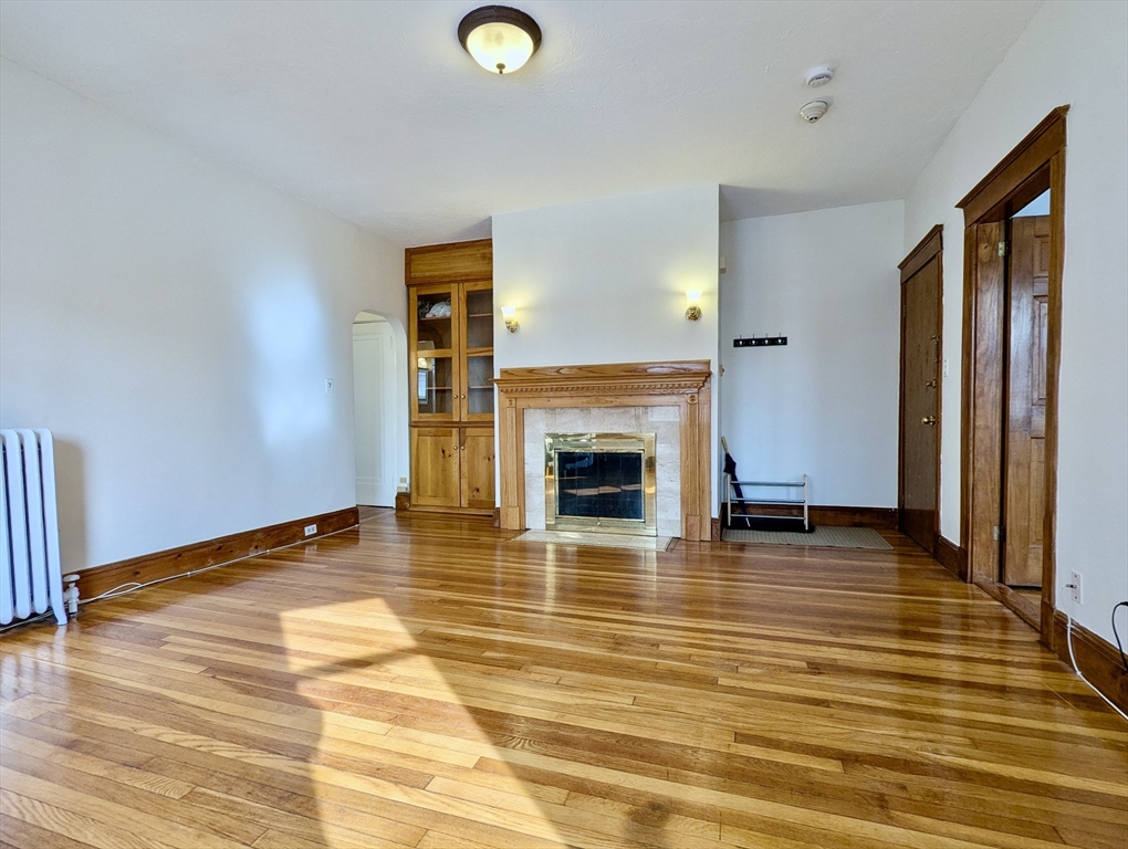 21 Westbourne Terrace, Unit 3 Brookline, MA 02446 - Photo 9 of 23 a view of an empty room with wooden floor and a fireplace