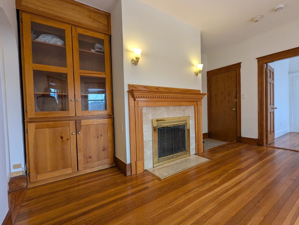 21 Westbourne Terrace, Unit 3 Brookline, MA 02446 - Photo 10 of 23 an empty room with wooden floor and a fireplace