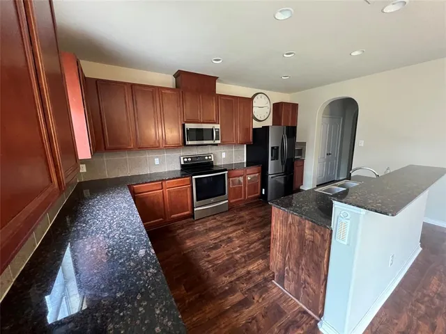 a kitchen with stainless steel appliances granite countertop a sink stove and refrigerator