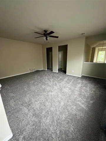 an empty room with chandelier fan and windows
