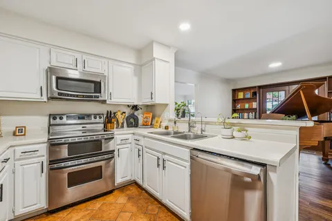 a kitchen with stainless steel appliances granite countertop a stove a sink and a microwave