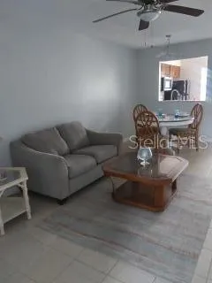 a living room with couches and kitchen view with wooden floor