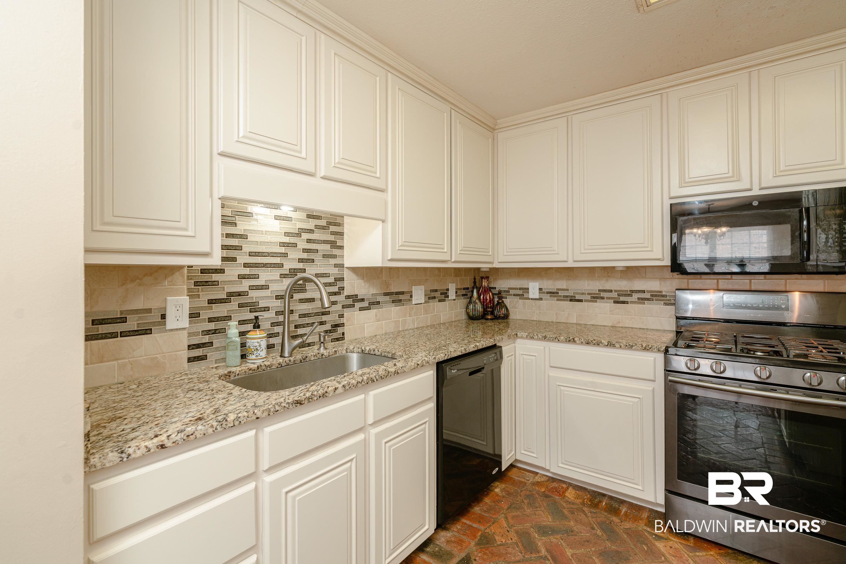 23 Old Mill Court Mobile, AL 36608 - Photo 14 of 37 Kitchen with decorative backsplash, white cabinetry, black appliances, and sink