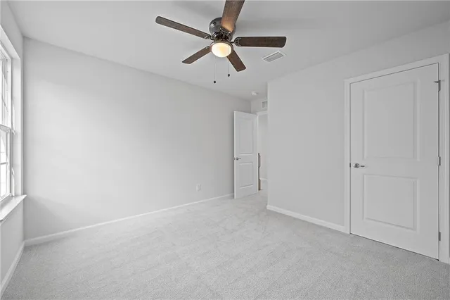 an empty room with a window and a fan