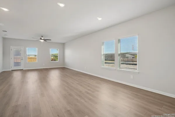 an empty room with wooden floor and windows