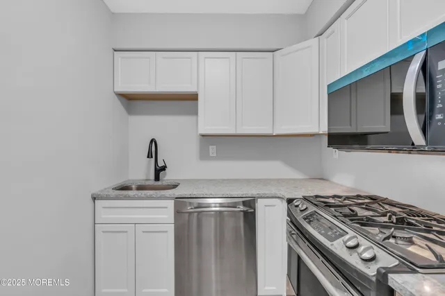 a kitchen with stainless steel appliances granite countertop a sink a stove and microwave