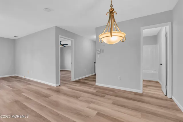 an empty room with wooden floor windows and a chandelier