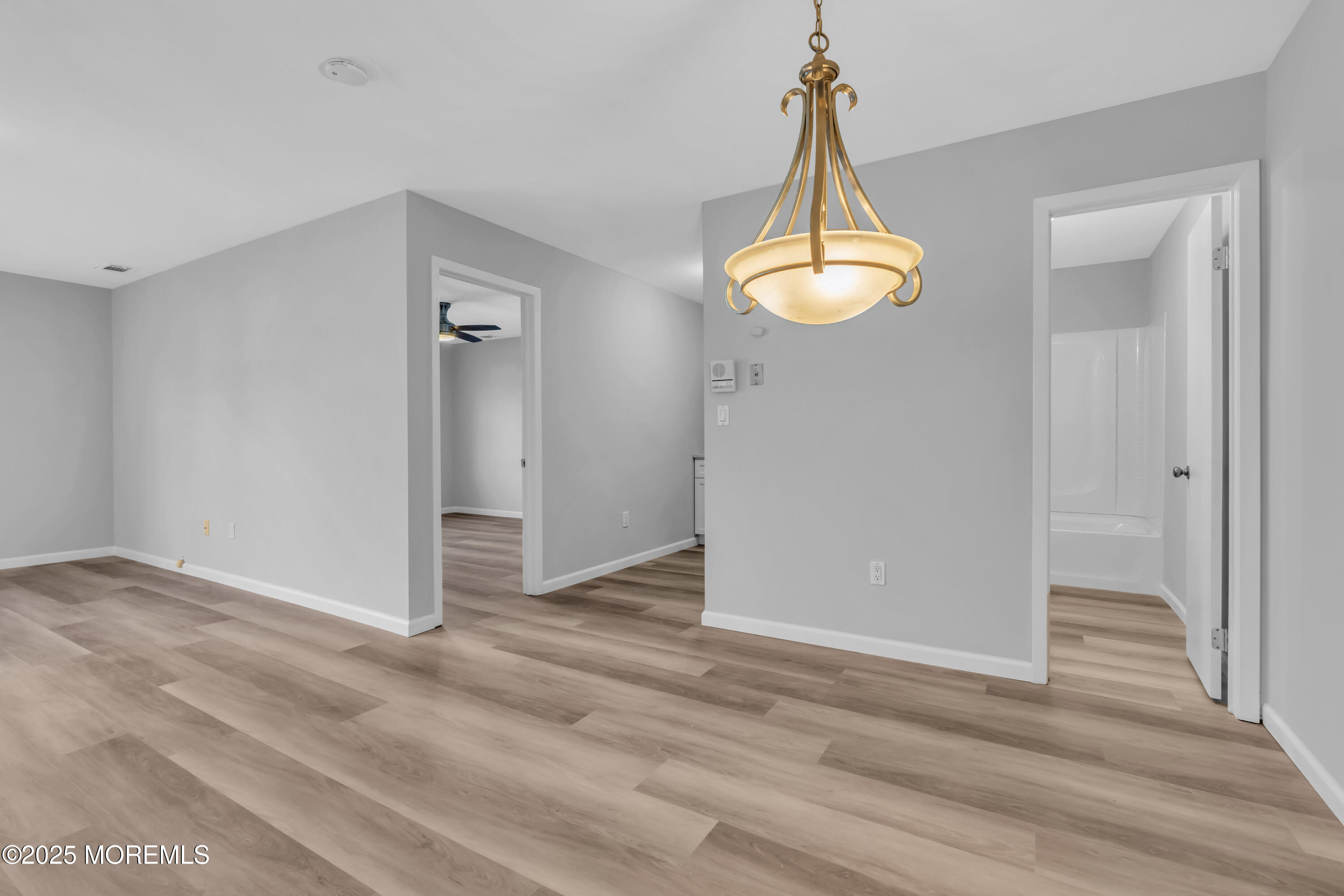 213 Main Street, Unit 17 Keansburg, NJ 07734 - Photo 9 of 15 an empty room with wooden floor windows and a chandelier