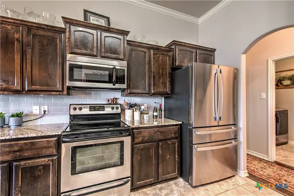 a kitchen with granite countertop a refrigerator stove and microwave