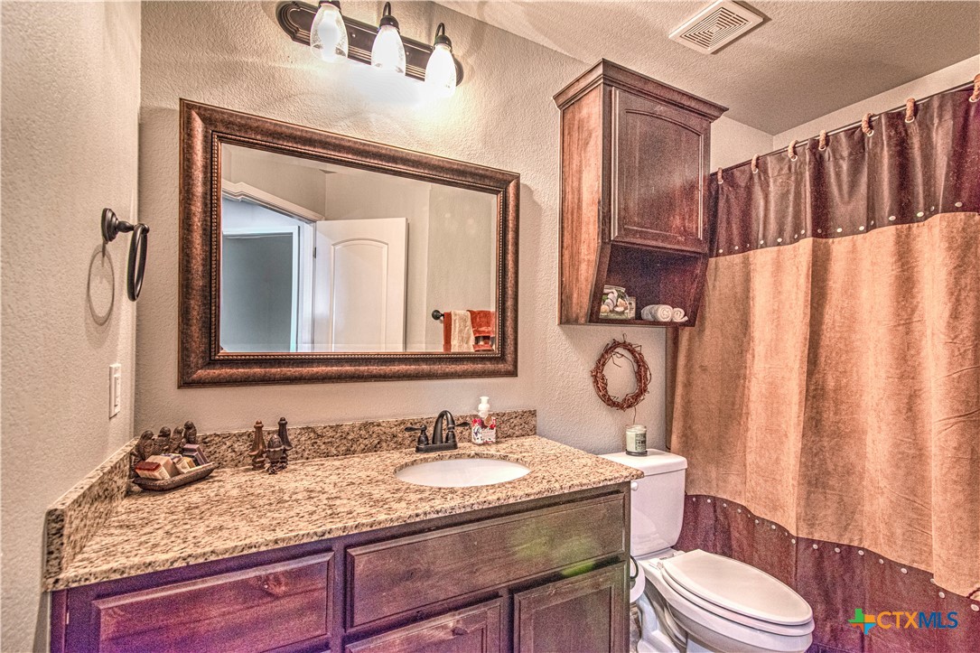 412 Dandridge Drive Temple, TX 76502 - Photo 30 of 44 a bathroom with a granite countertop sink vanity mirror and toilet