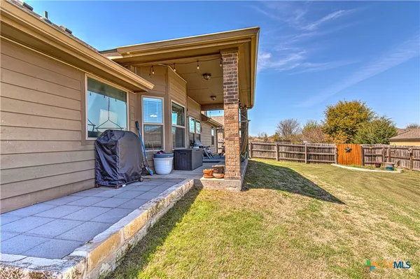 a view of backyard with barbeque grill and wooden fence