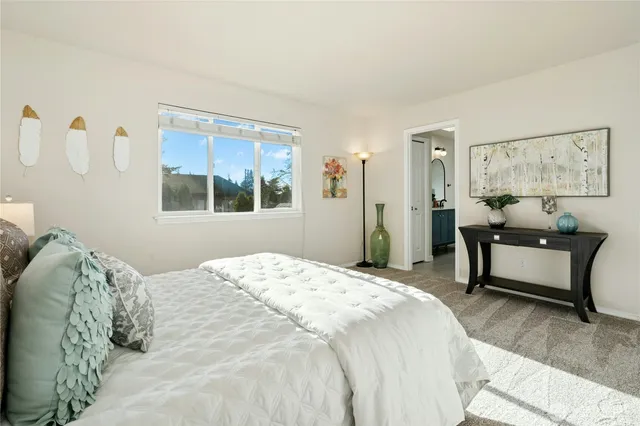 a bedroom with a bed table chair and window